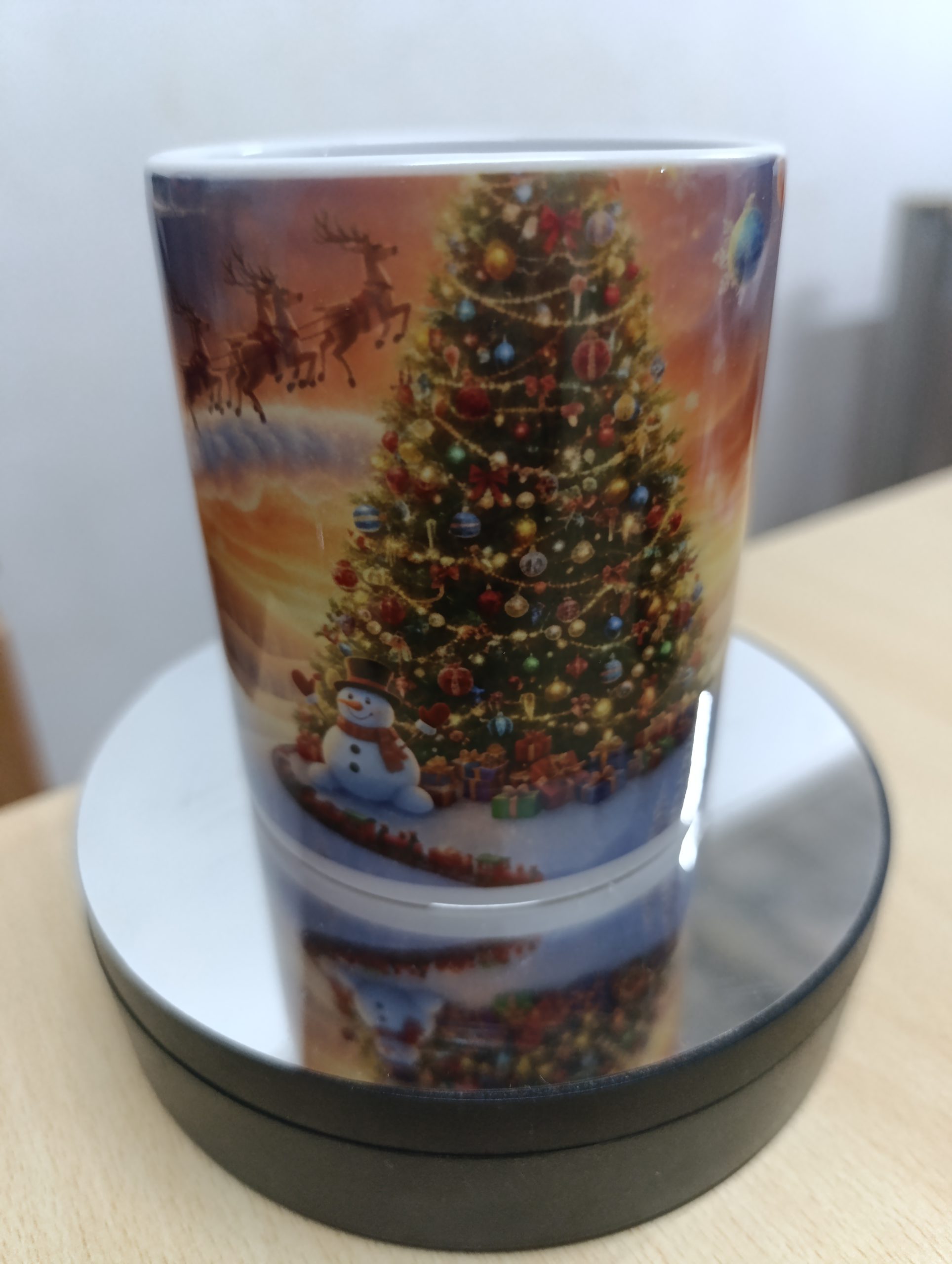Ceramic mug with colorful Christmas scene featuring Santa, reindeer, snowman, and a decorated Christmas tree