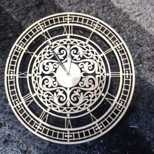 Laser-cut wooden wall clock with Roman numerals and ornate cut-out centre design